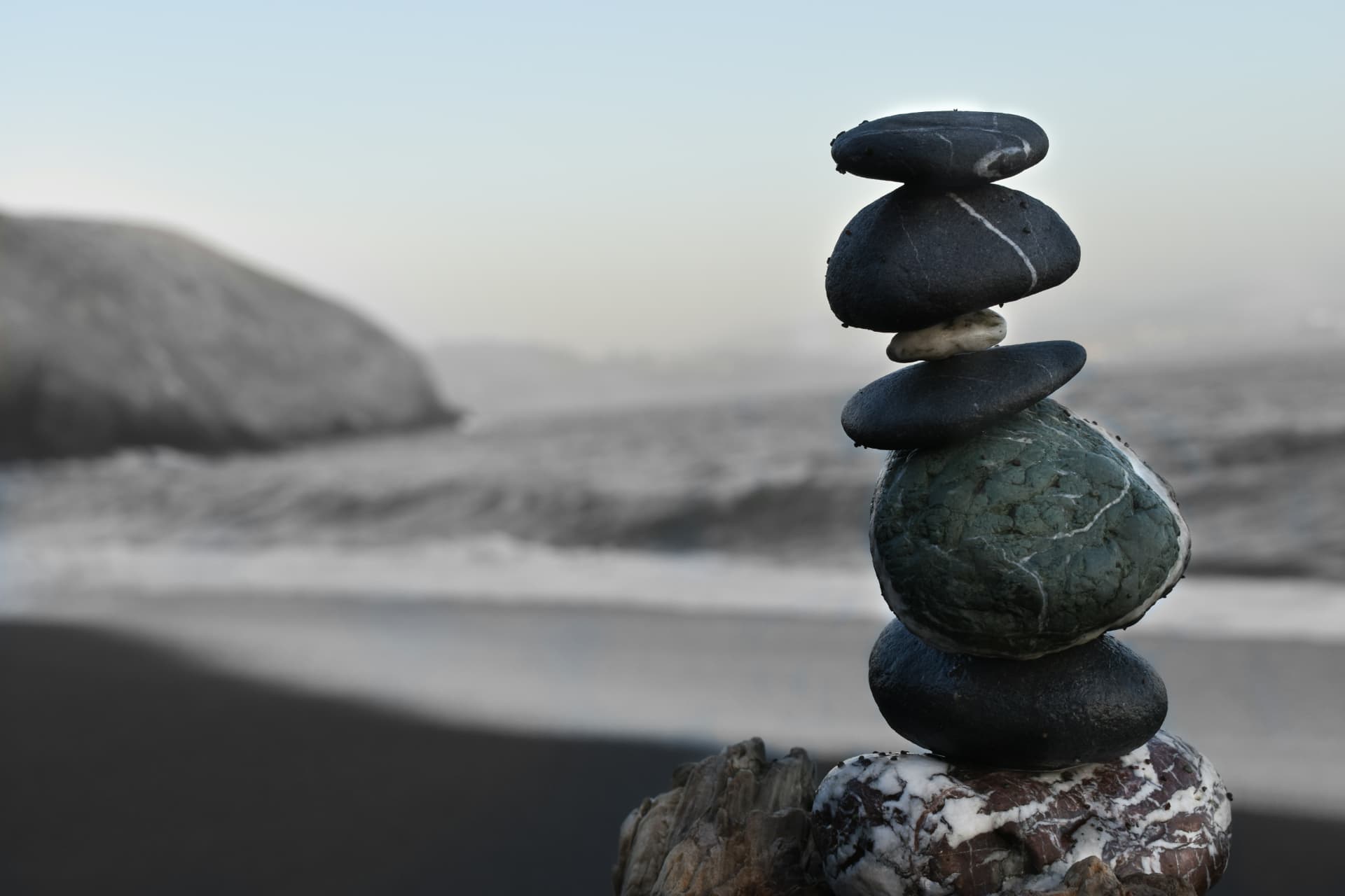 Balanced stack of smooth stones on a quiet shore at dawn
